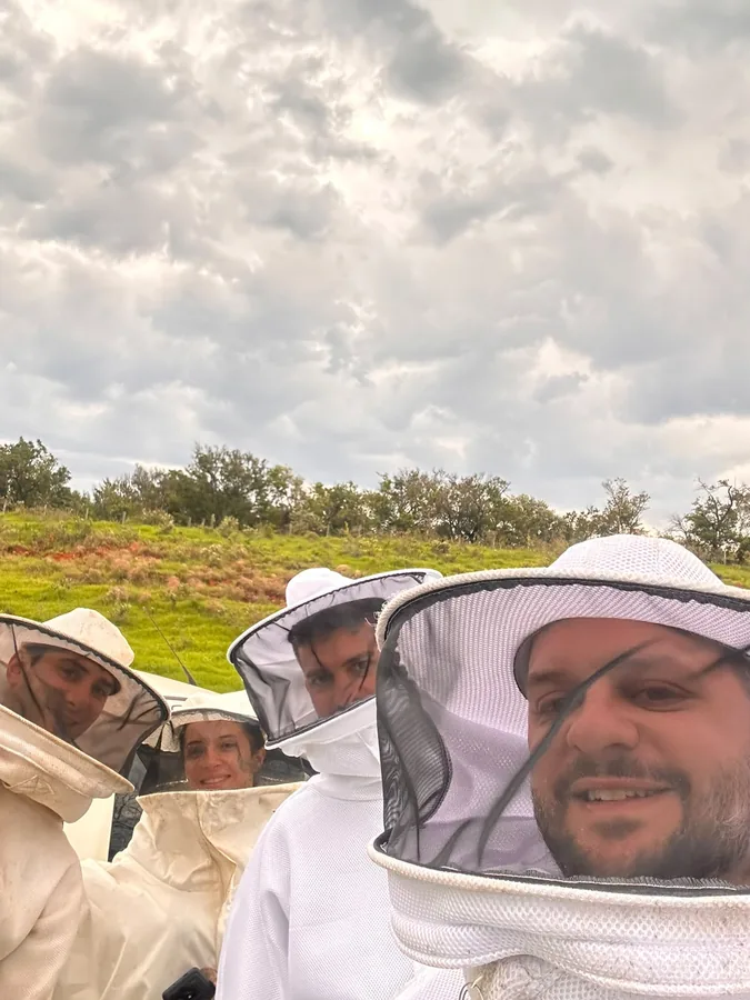 Apicultores de véu e roupa de proteção posando para uma foto na fazenda
