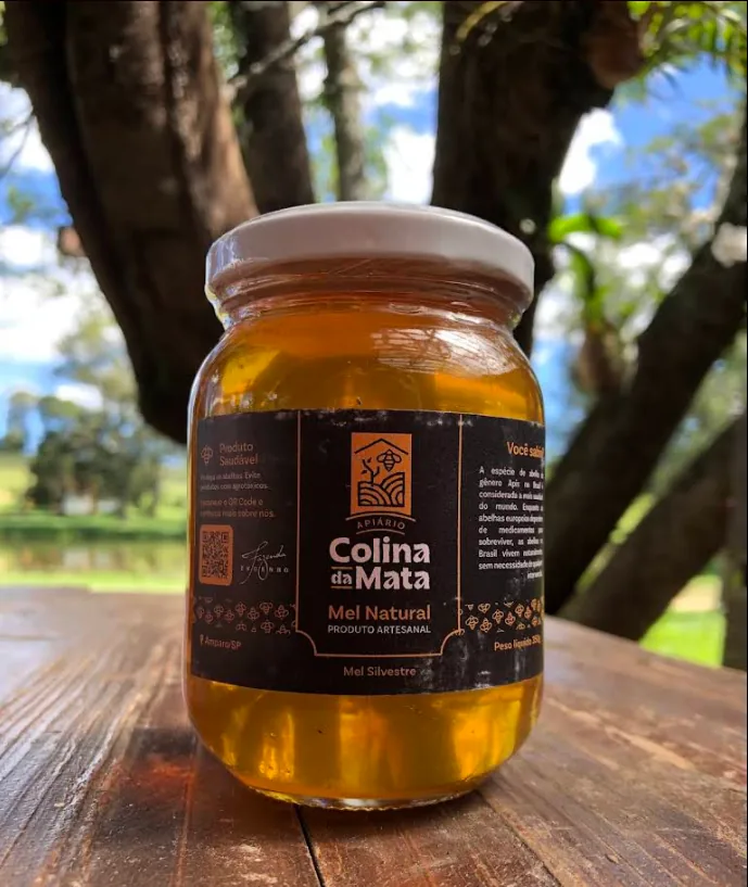 Pote de mel da Colina da Mata sobre a mesa de madeira sob as árvores da fazenda