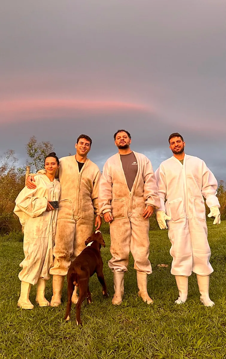 Equipe do Apiário Colina da Mata de roupa de apicultor na fazenda, ao entardecer